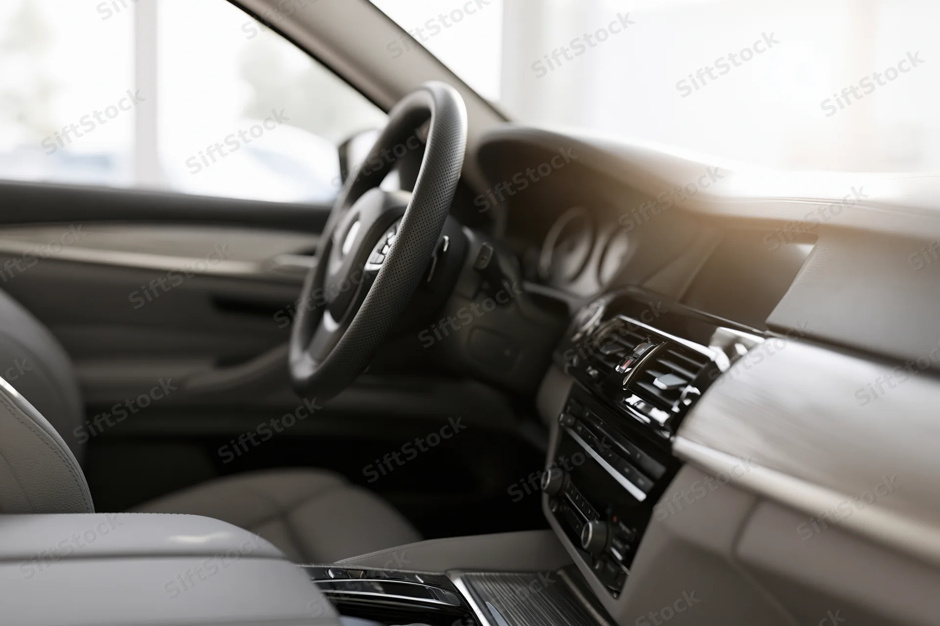 Luxury sedan interior viewed from passenger side showing steering wheel dashboard and seats