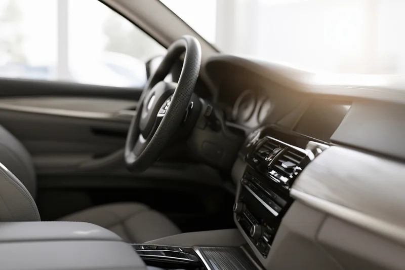 Luxury sedan interior viewed from passenger side showing steering wheel dashboard and seats