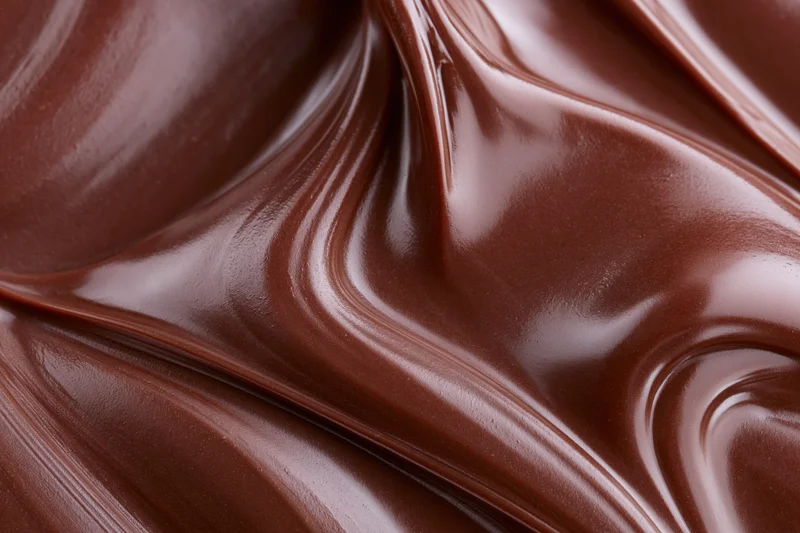 Melted dark chocolate flowing in swirling waves filling the frame