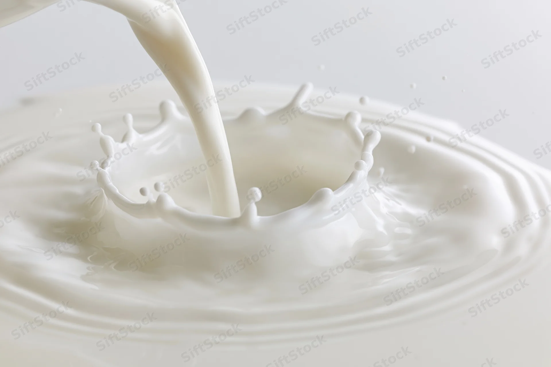 Milk being poured into a shallow pool creating a splash crown