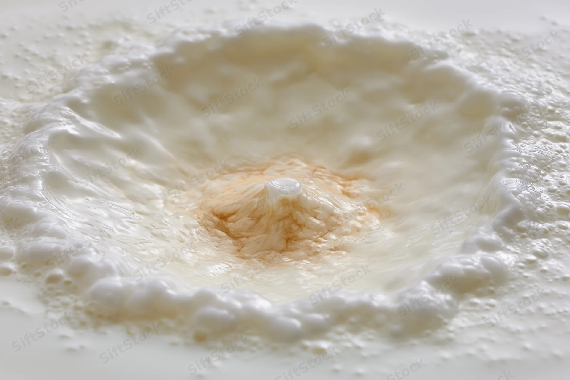 Milk being poured into a pool creating a crown splash with foam and ripples