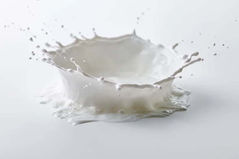Milk splash frozen mid-motion forming a crown shape against white background