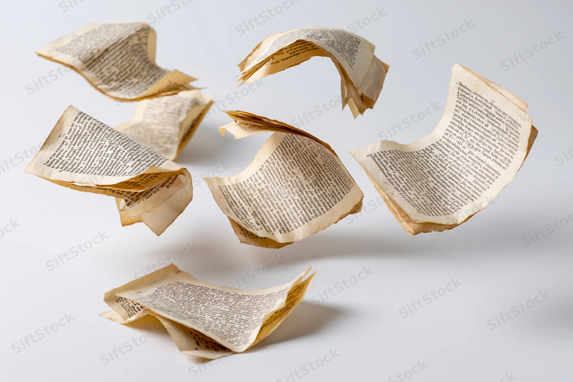 Aged paper pages with printed text tumbling in midair against a white background