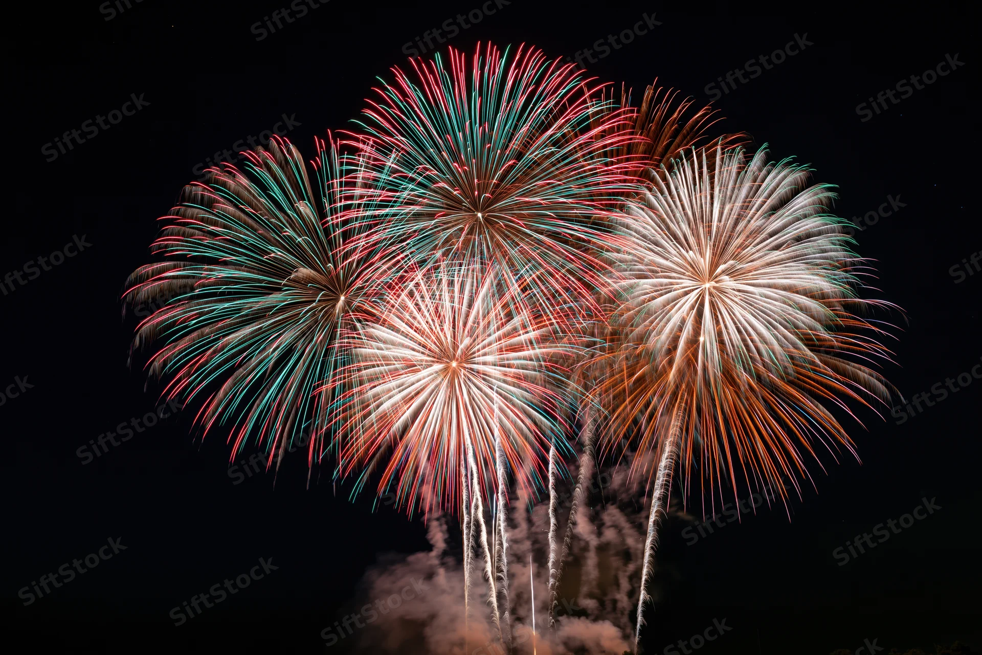 Multiple fireworks bursting simultaneously in the dark night sky