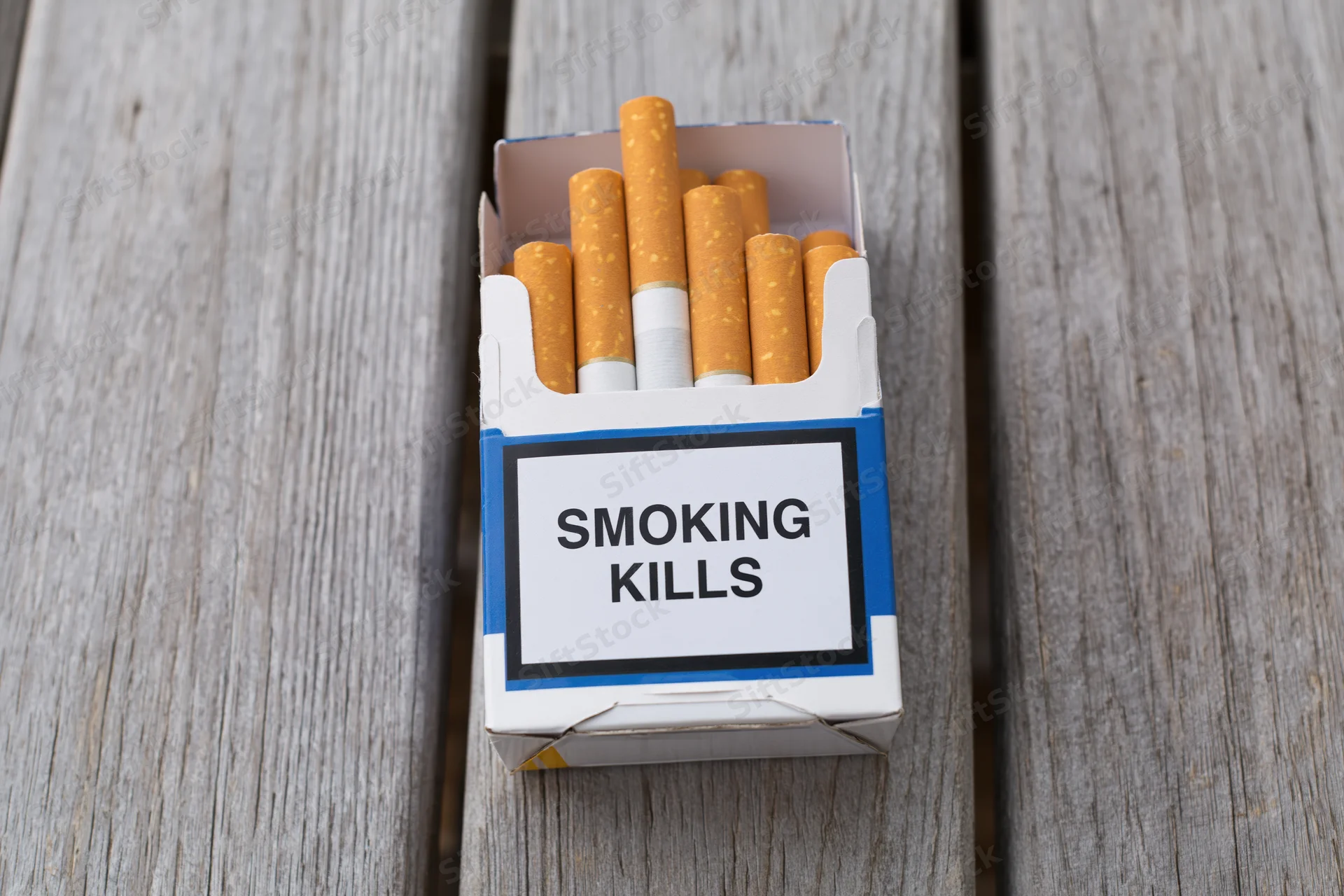 Open cigarette pack with smoking kills warning label on wooden surface