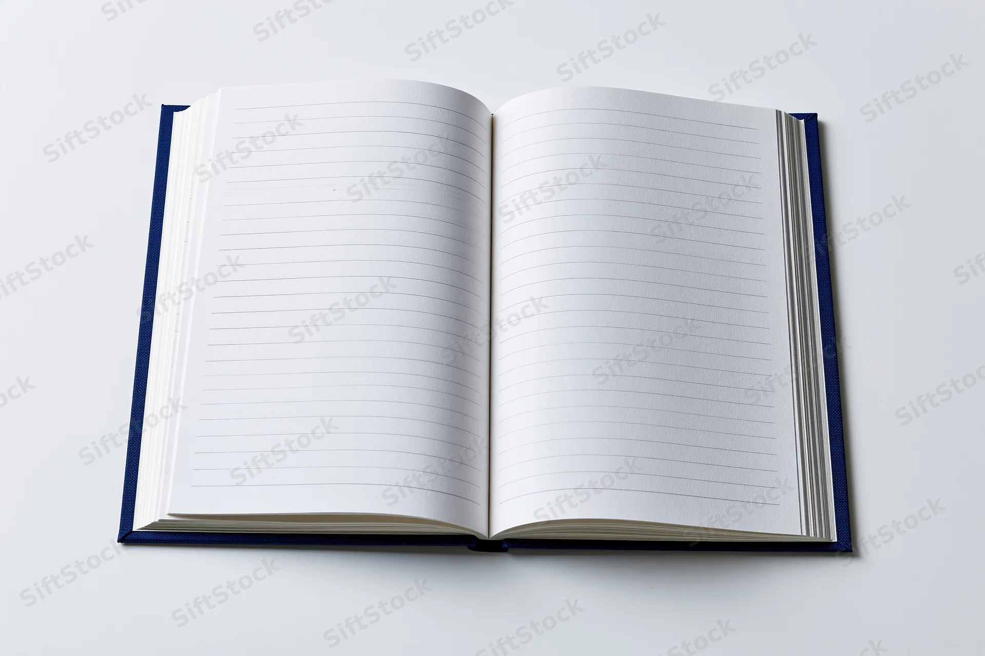 Open hardcover notebook with navy blue cloth binding lying flat on white surface showing blank lined pages