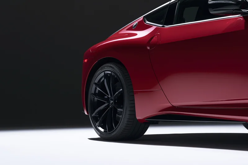 Red electric sports car side profile from low rear threequarter angle in studio lighting