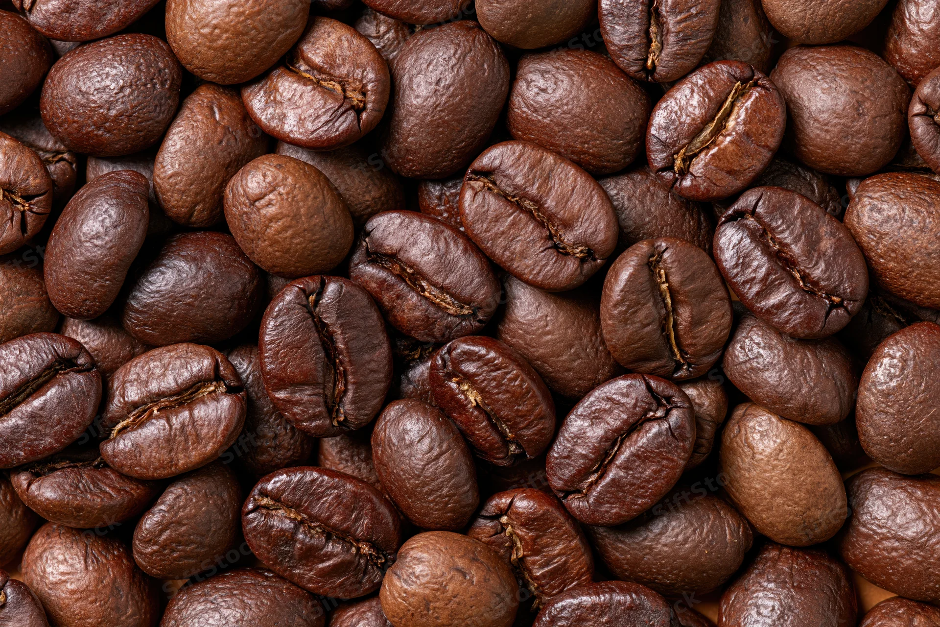 Roasted coffee beans filling the frame edge to edge in a closeup texture view