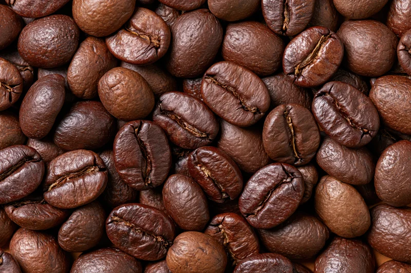 Roasted coffee beans filling the frame edge to edge in a closeup texture view