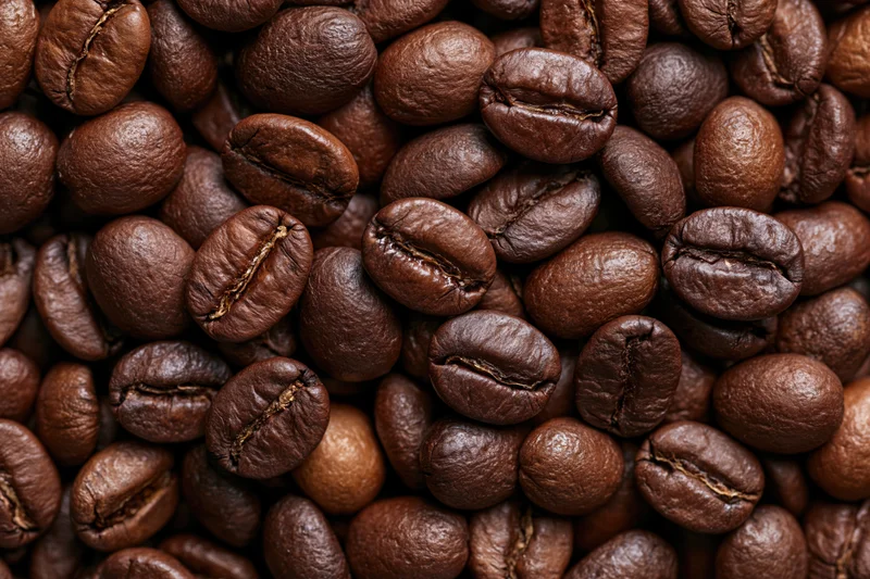 Roasted coffee beans filling the frame in a closeup texture view