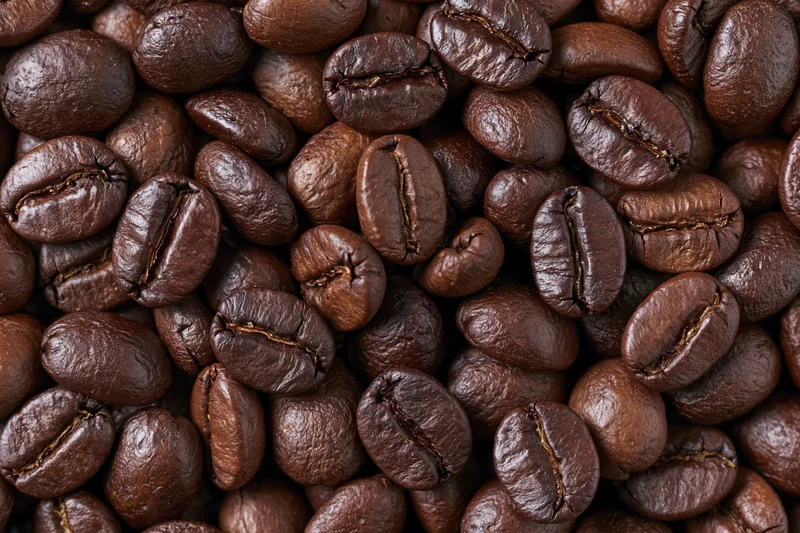 Roasted coffee beans filling the frame edge to edge in a closeup texture view