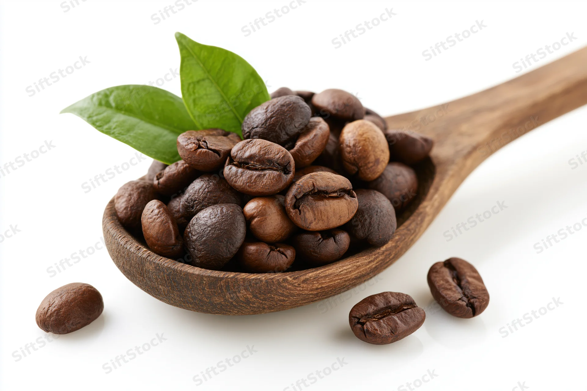Roasted coffee beans in a wooden spoon with a green leaf on white background