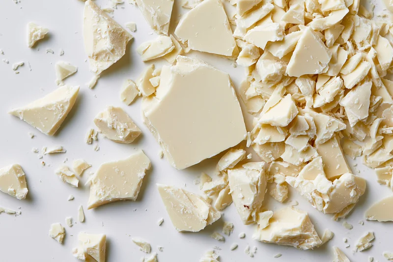 Broken white chocolate pieces scattered on a white surface