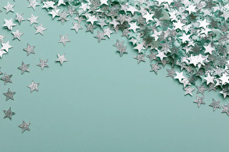 Silver and white star-shaped glitter confetti scattered across a mint green surface with copyspace