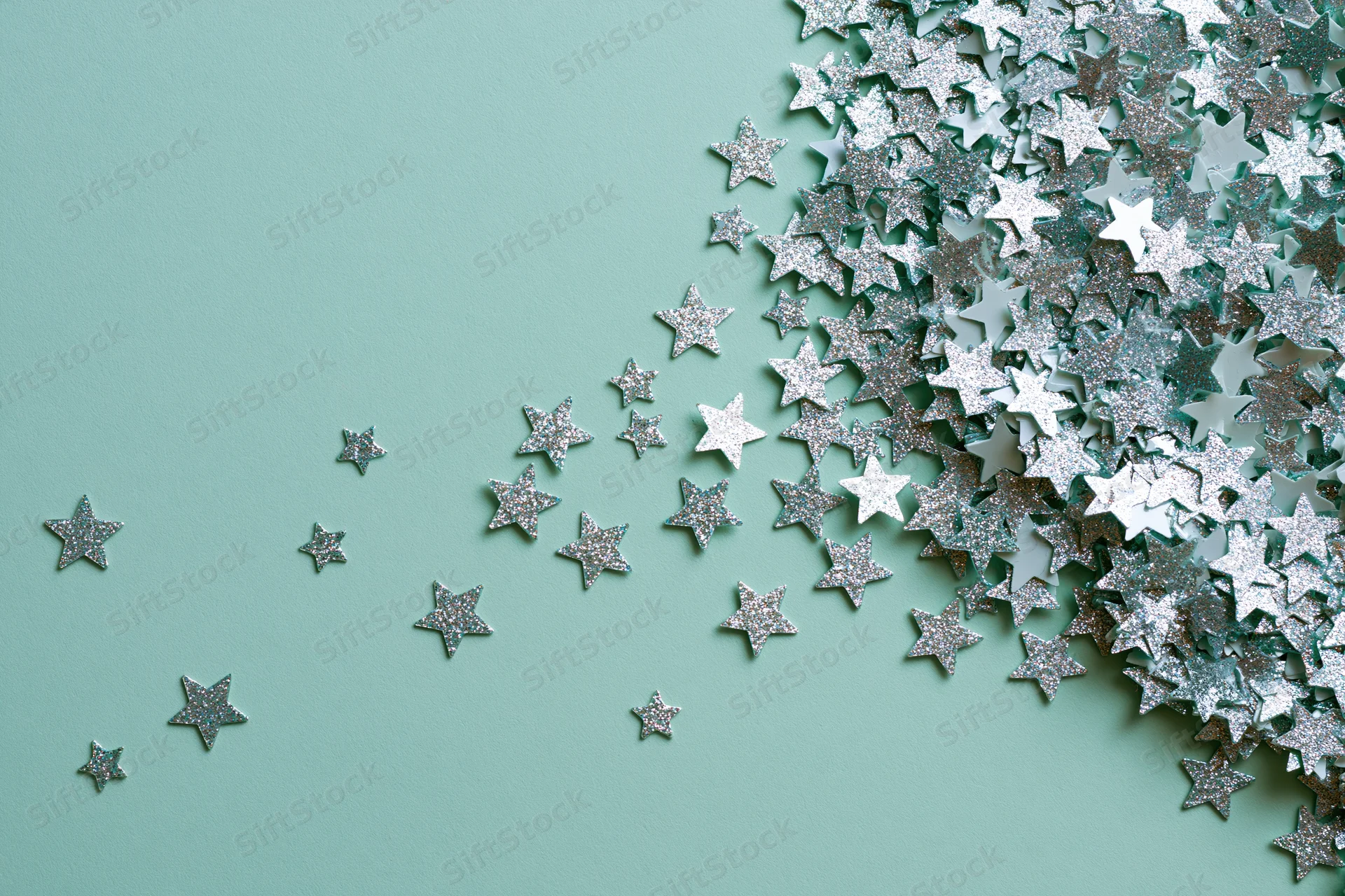 Silver and white star-shaped glitter confetti scattered across a mint green surface