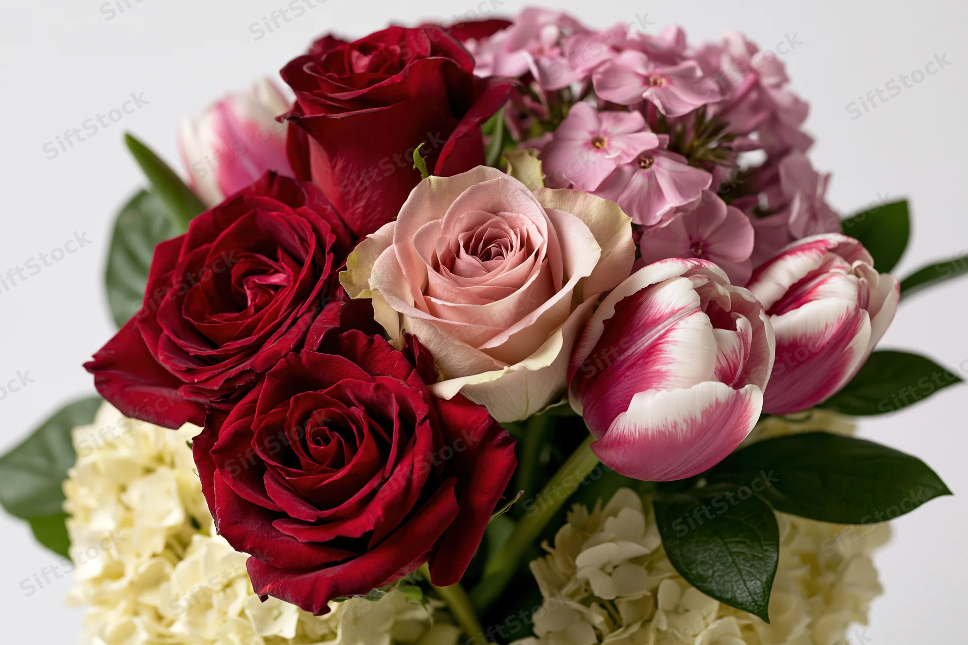 Close-up of a floral bouquet with red roses, pink tulips, white hydrangeas and green leaves on a white background