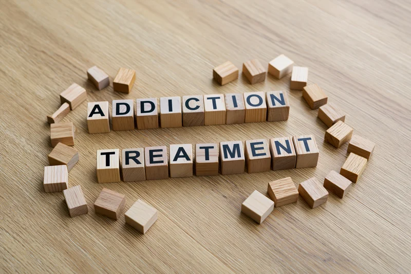 Wooden letter cubes spelling addiction treatment on a light oak surface