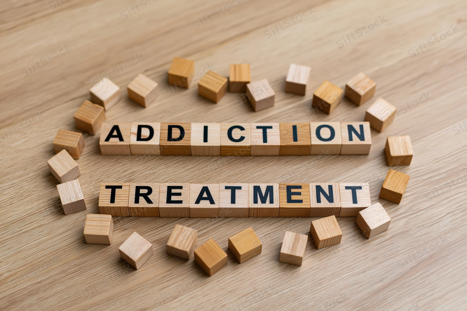 Wooden letter cubes spelling addiction treatment on a light oak surface