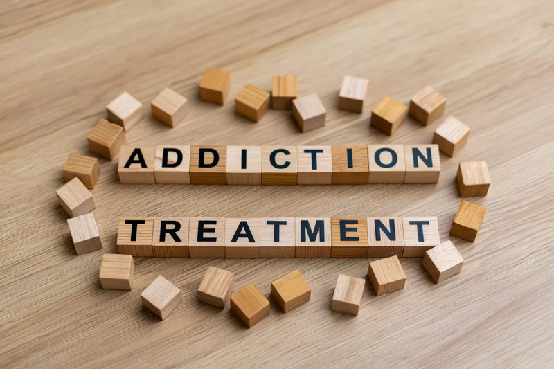 Wooden letter cubes spelling addiction treatment on a light oak surface
