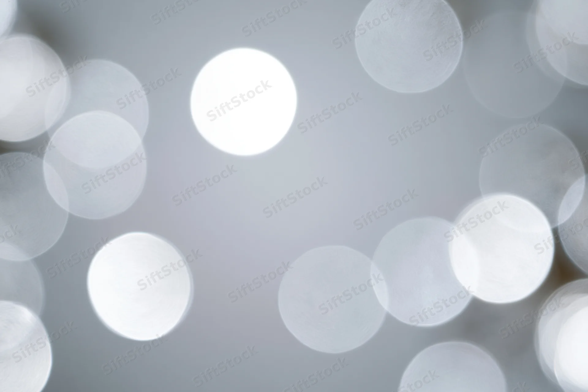 Soft white bokeh circles floating against a smooth gray background