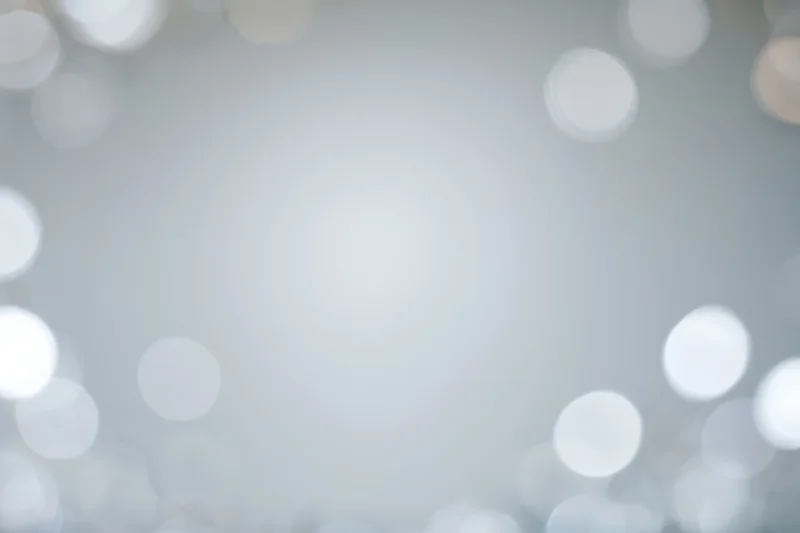 Soft out-of-focus bokeh circles floating against a smooth light gray background with copyspace in center