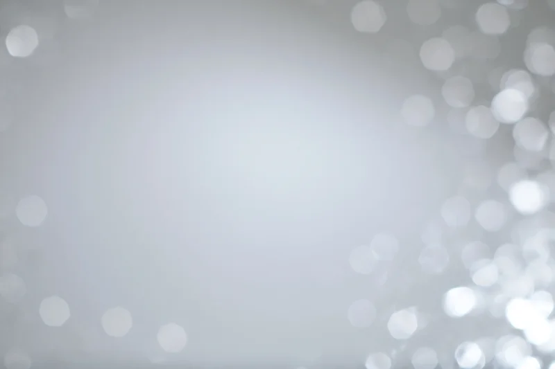 Soft white bokeh lights scattered across a smooth background with copyspace