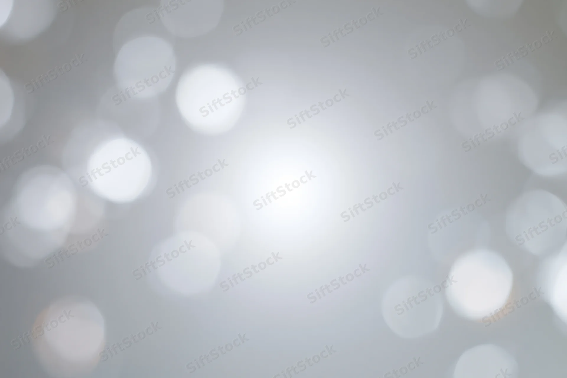 Soft white bokeh circles floating against a smooth gray gradient background