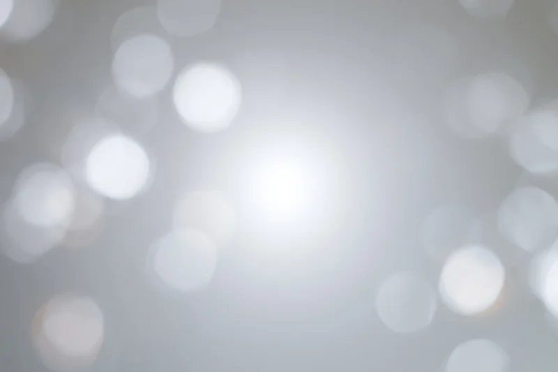 Soft white bokeh circles floating against a smooth gray gradient background