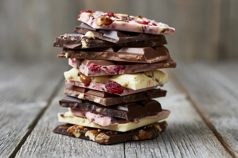 Stack of assorted broken chocolate bar pieces piled high on a rustic wooden table