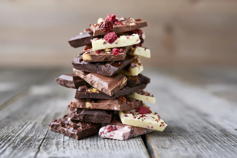 Stack of assorted broken chocolate pieces piled high on a rustic wooden table