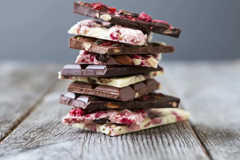 Stack of assorted broken chocolate bar pieces piled high on a rustic wooden table