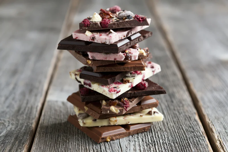 Stack of assorted broken chocolate pieces piled high on a rustic wooden table