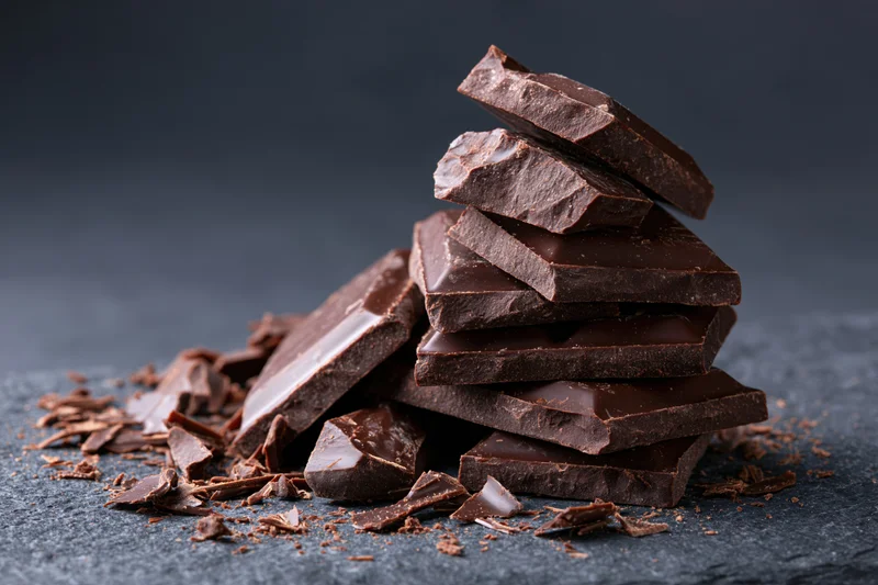 Broken dark chocolate chunks piled on a rough slate surface