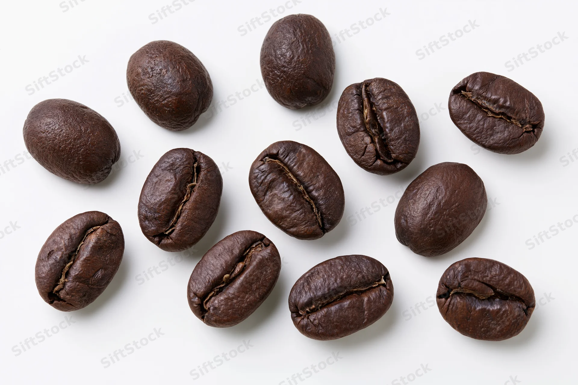 Roasted coffee beans scattered on a white surface in a top-down view