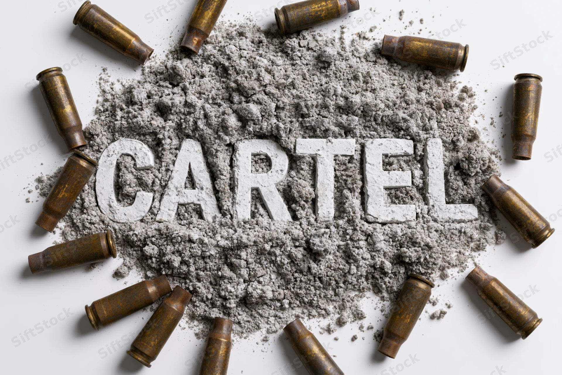 The word cartel spelled in white letters pressed into gray powder surrounded by bullet casings on white surface