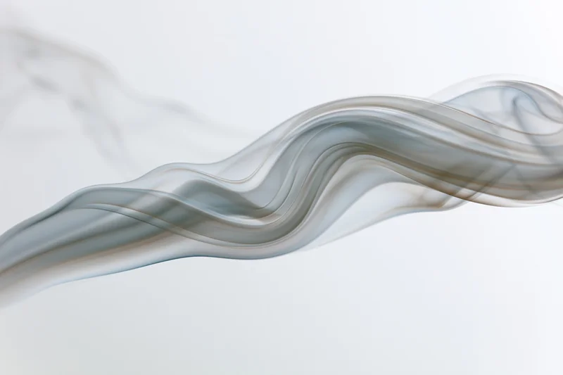Thin wisp of white smoke curling and rising in soft undulations against a plain background
