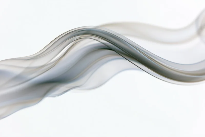 Thin wisp of white smoke curling and rising in soft undulating motion against a plain white background