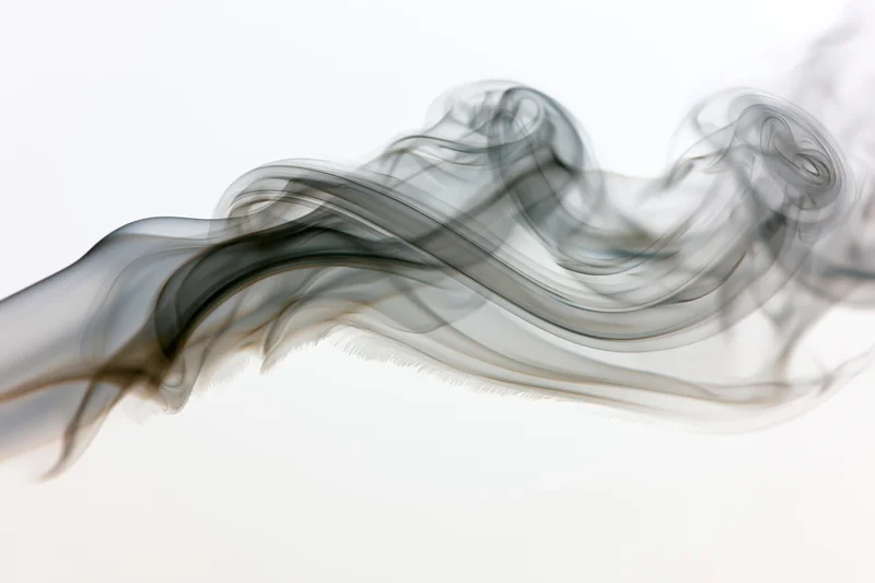 Dark smoke curling and drifting across a white background