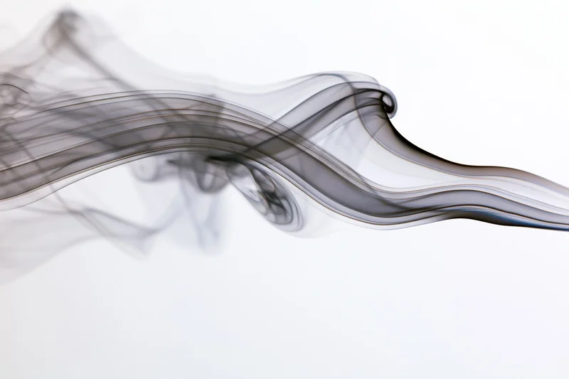 Dark smoke wisps curling and drifting across a white background