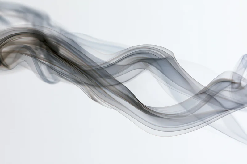 Thin gray smoke drifting in flowing curves across a white background