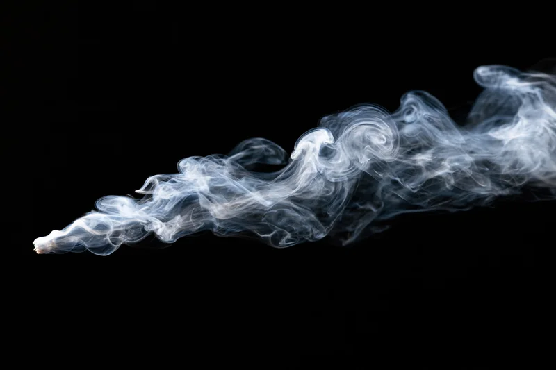White smoke curling and dispersing against a black background