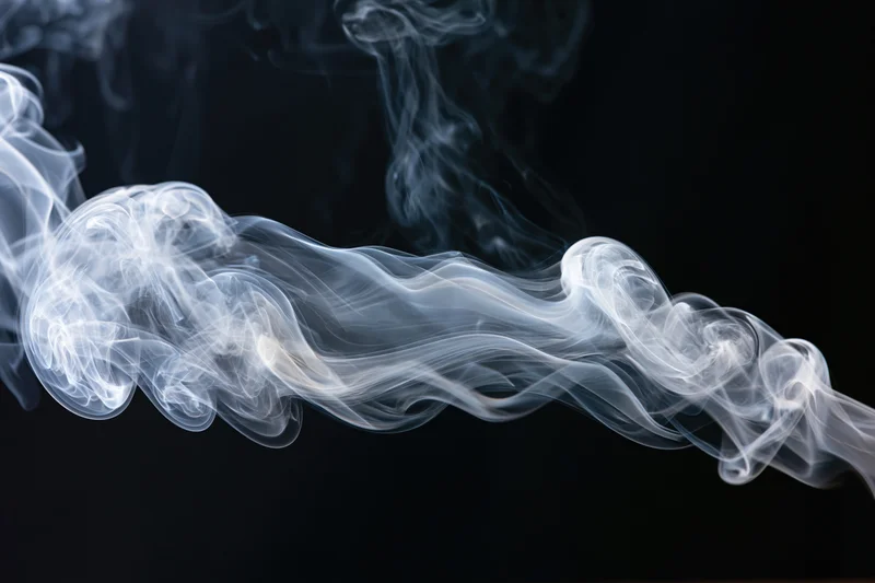 White smoke curling and dispersing in mid-air against a black background
