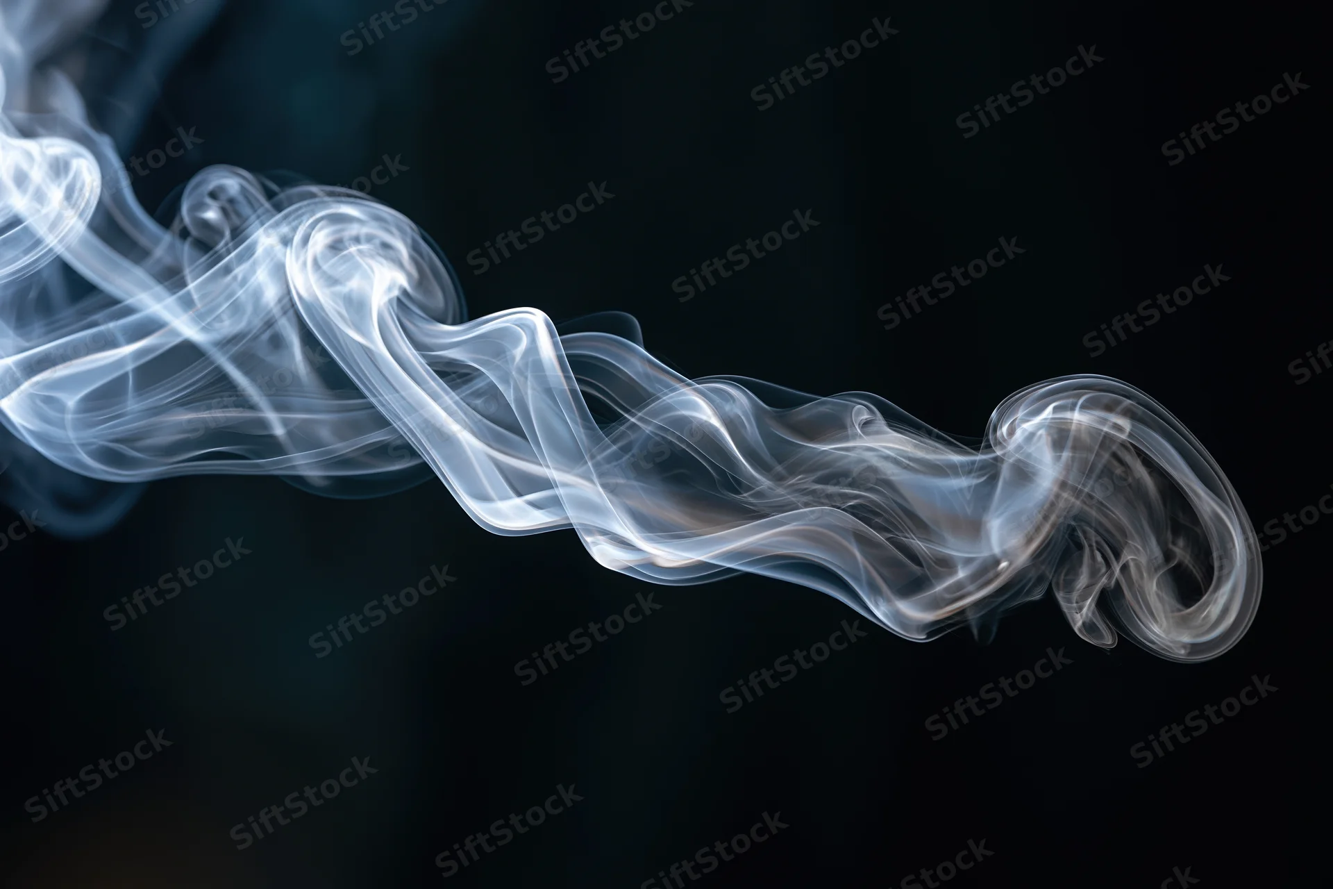 White smoke curling and dispersing midair against a dark background