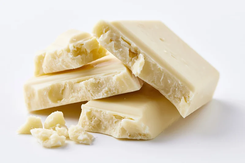 Broken white chocolate pieces stacked casually on a white surface