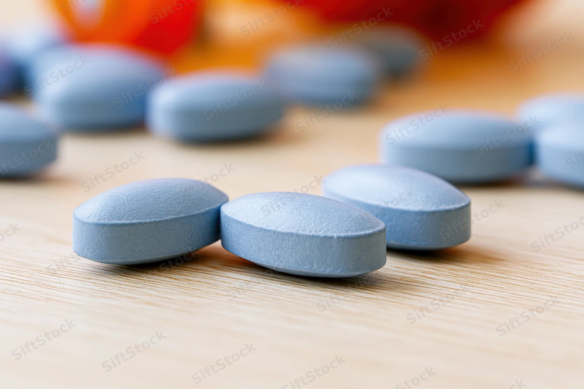 Pale blue oval tablets resting on a light wood surface