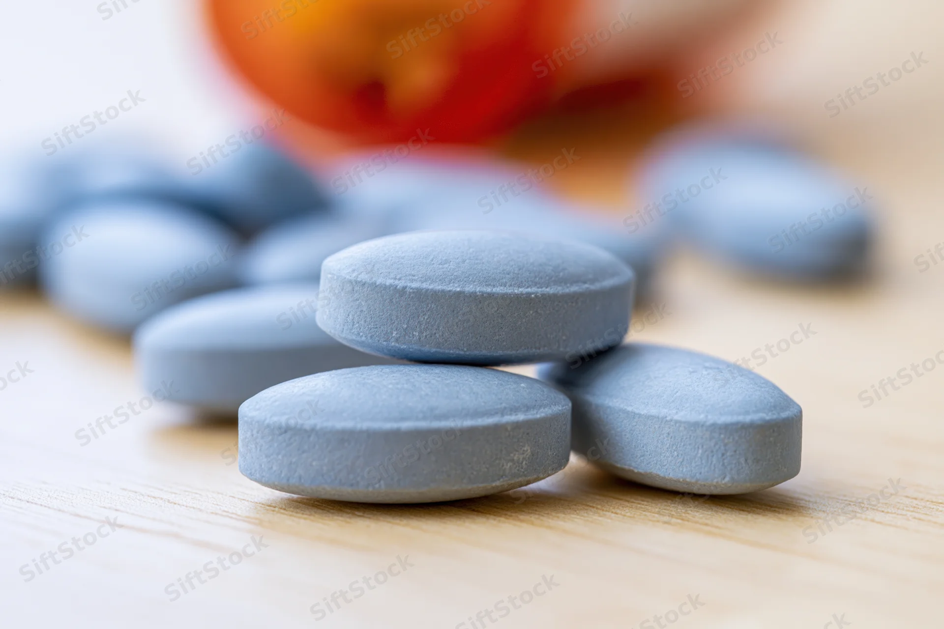 Pale blue oval tablets resting on a light wood surface