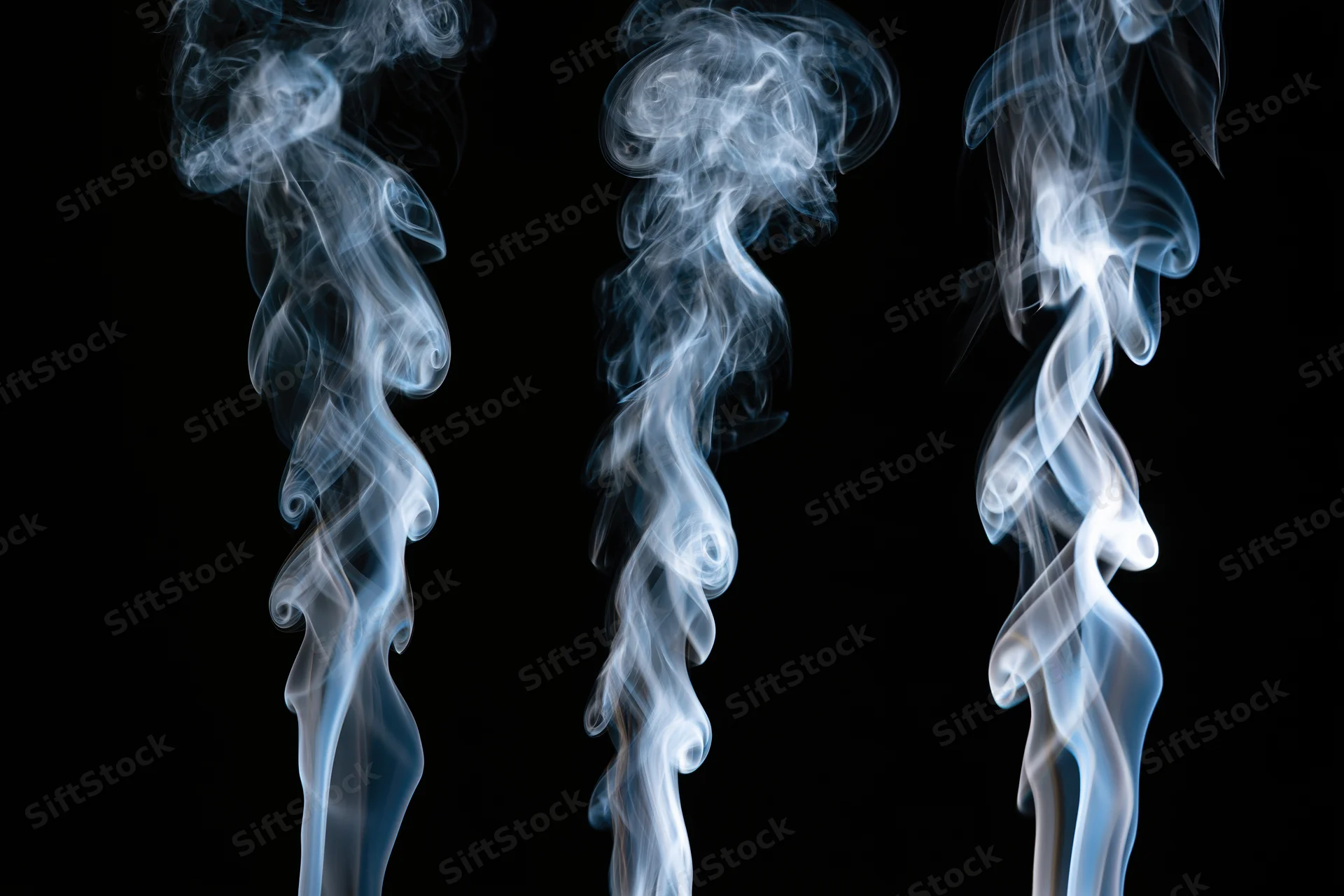 Three columns of rising white and pale blue smoke against a black background