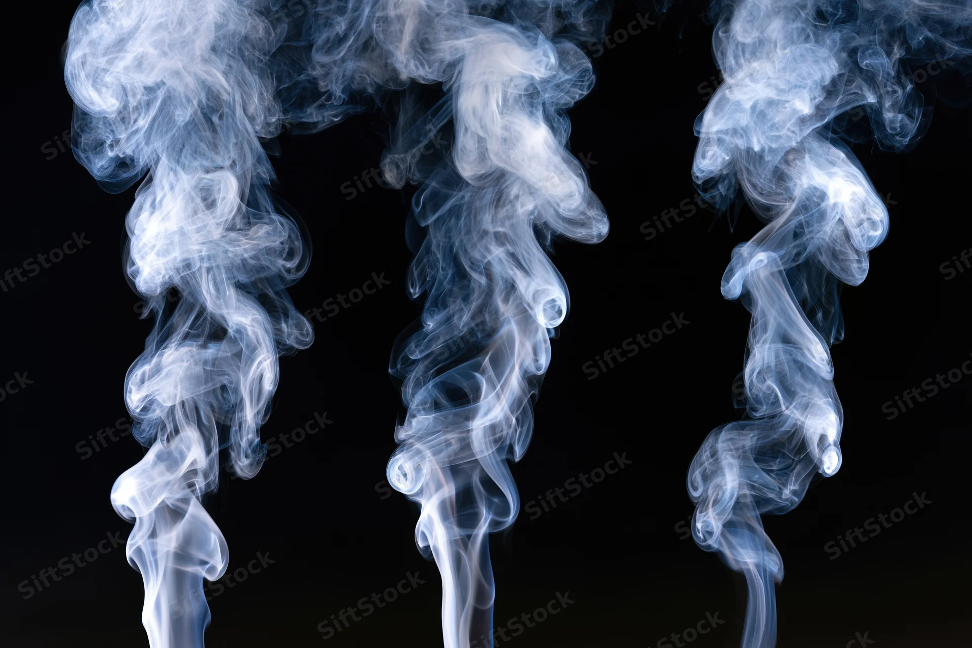 Three columns of white and pale blue smoke rising against a black background