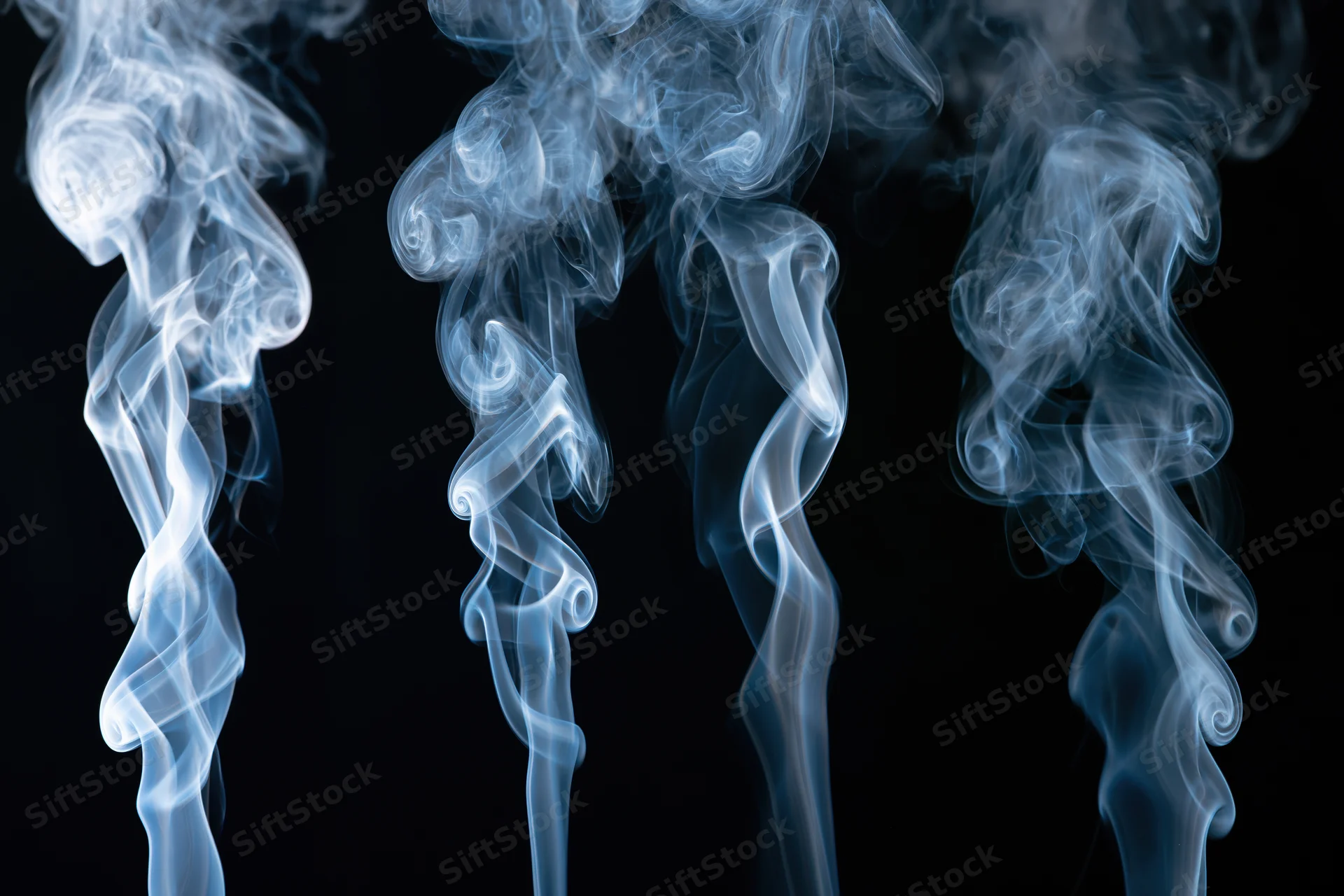 Three columns of rising white and pale blue smoke against a black background