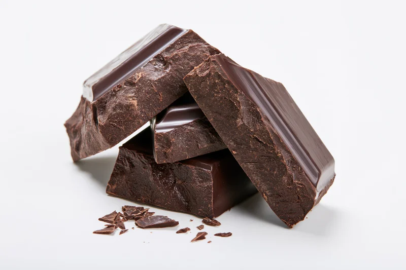 Dark chocolate chunks stacked with broken edges on white background